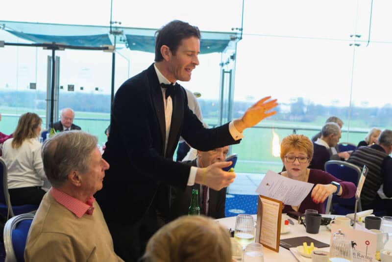 Magician wows guests with fire trick at a Christmas social event.