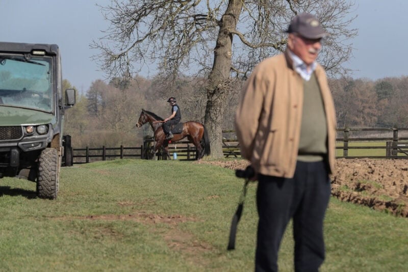 An owner holds a camera after watching a racehorse exercise