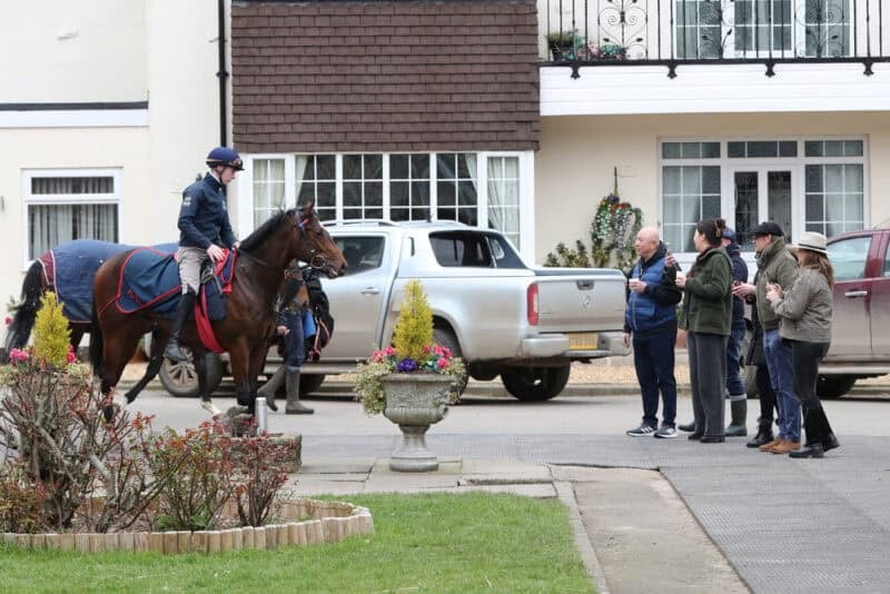 Owners watching their horse return to Karl Burke's yard after exercise