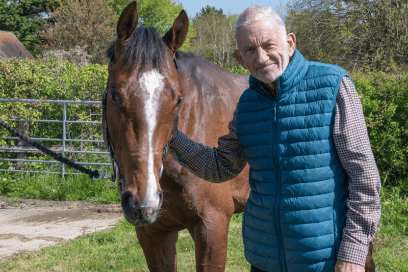 An owner poses for a photo with his racehorse.