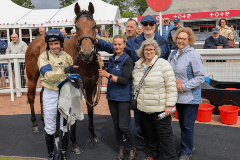 Jockey Tom Eaves smiles with the racehorse Belsito and his owners in the winners enclosure at Hamilton Park Racecourse after winning