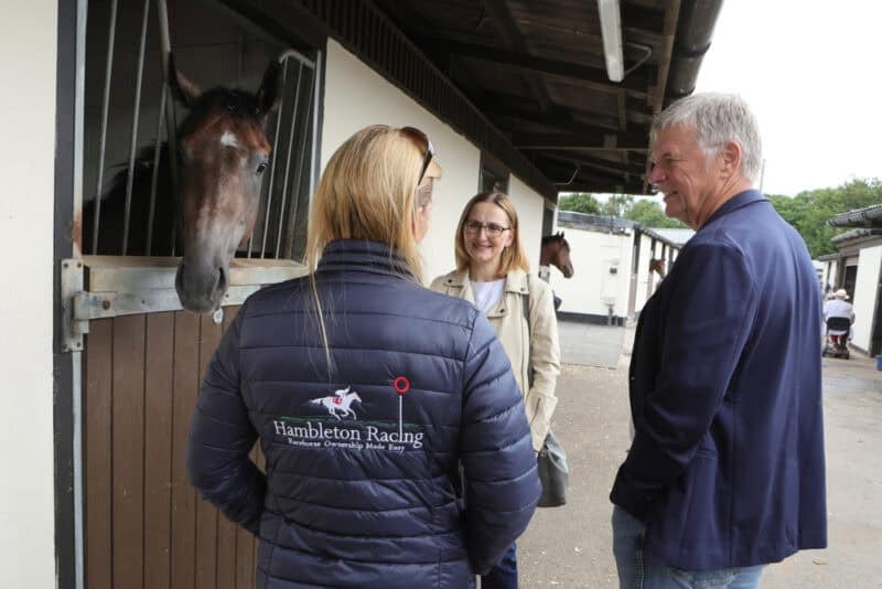 a member of the Hambleton racing team chats to owners at the stables