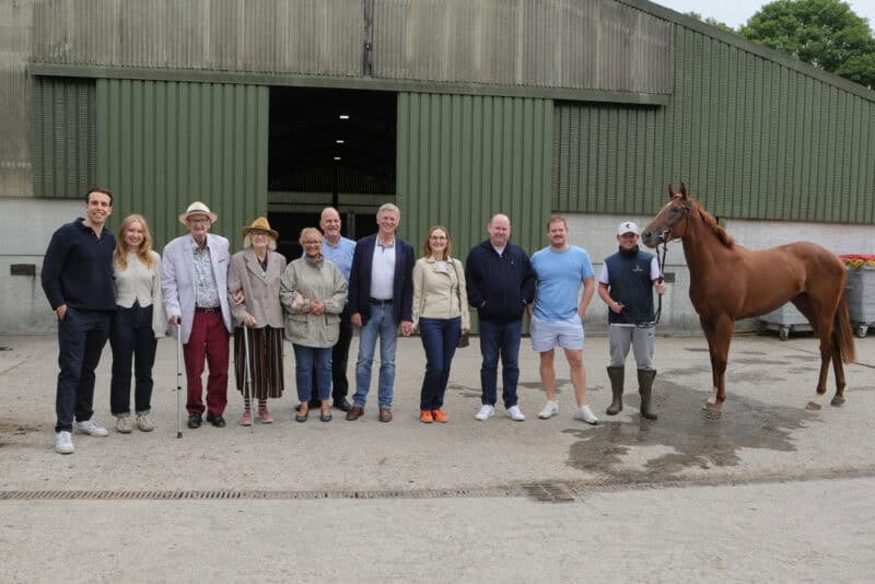 a group of owners stand with their new racehorse